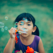 Young girl with bubbles at summer camp is happy she does not have lice because her parents followed summer lice prevention tips